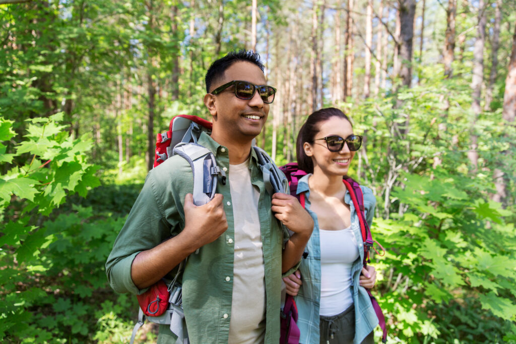 Selbsttönende Brillengläser für Licht und Schatten zwei menschen wandern mit sonnenbrille durch den wald
